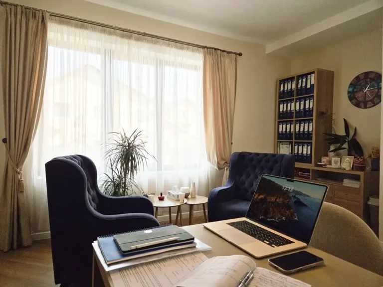 laptop deschis pe birou alaturi de agenda